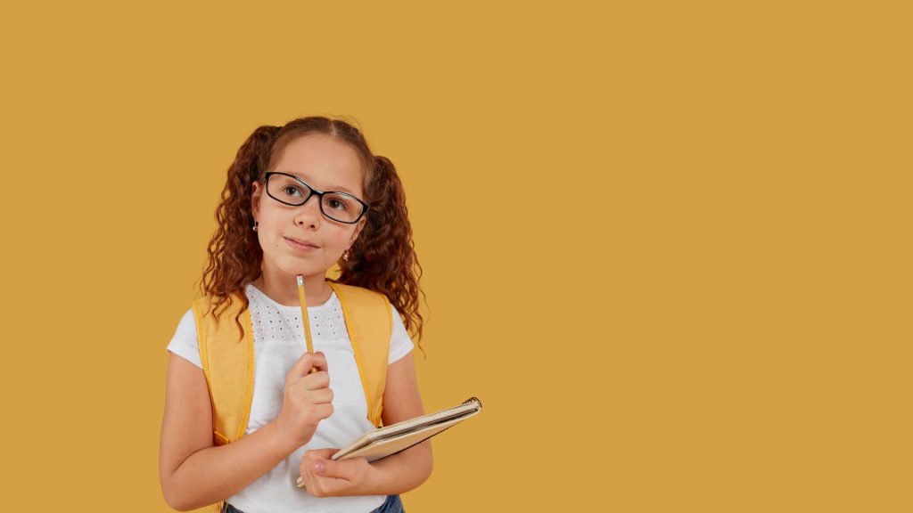 Portrait d'une élève en photographie scolaire tenant un crayon et un cahier dans les mains