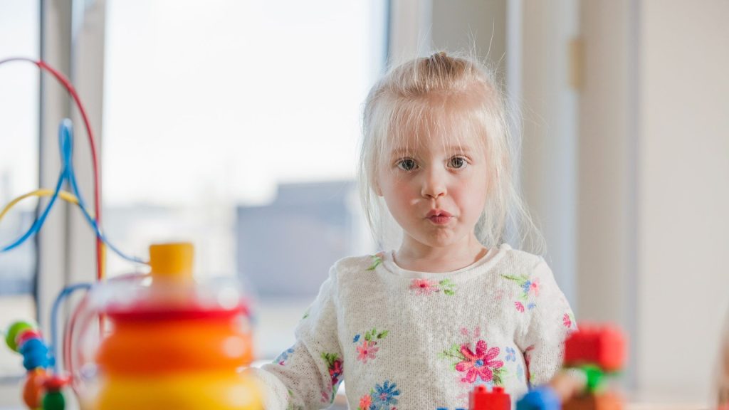 Une petite fille de maternelle devant des jeux d'éveils