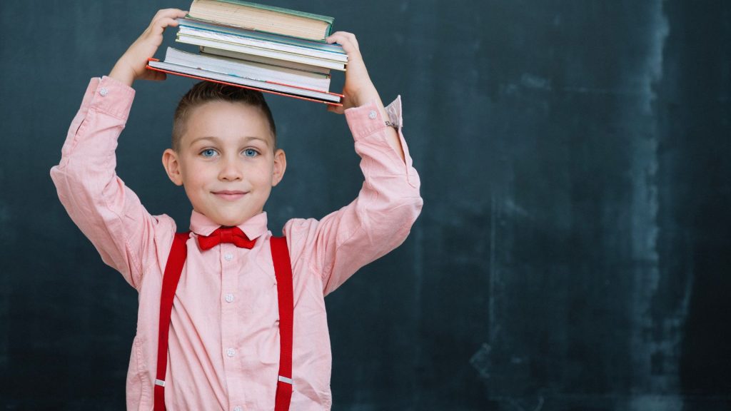 Photo d'un enfant d'école élémentaire tenant ses cahiers devant un tableau